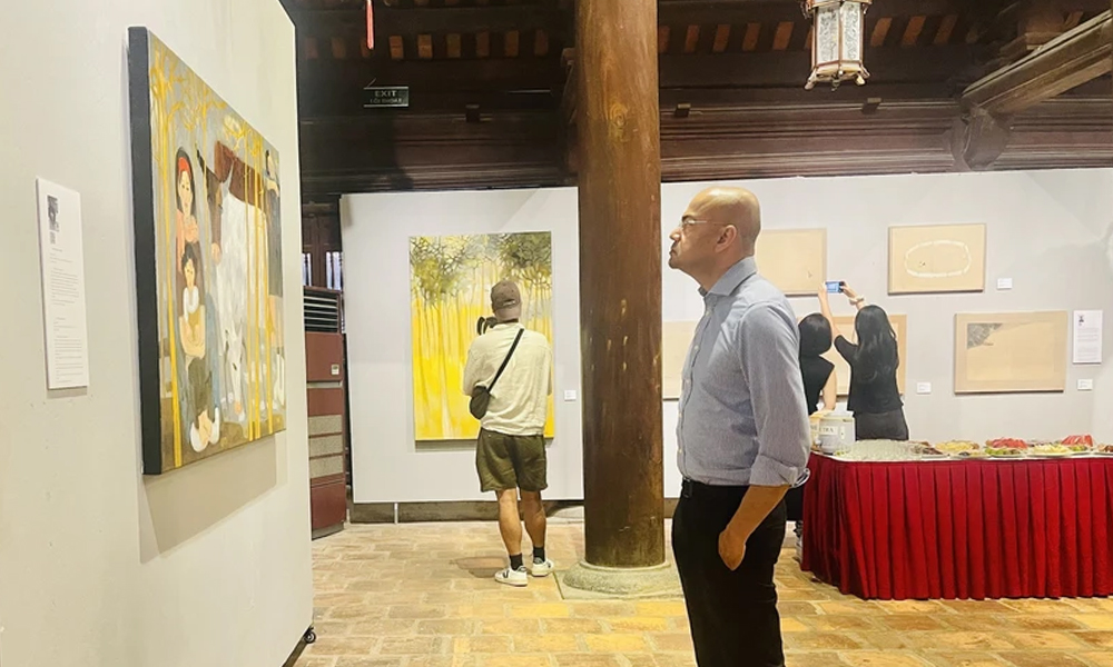Một du khách nước ngoài chăm chú trước một tác phẩm trưng bày tại triển lãm.