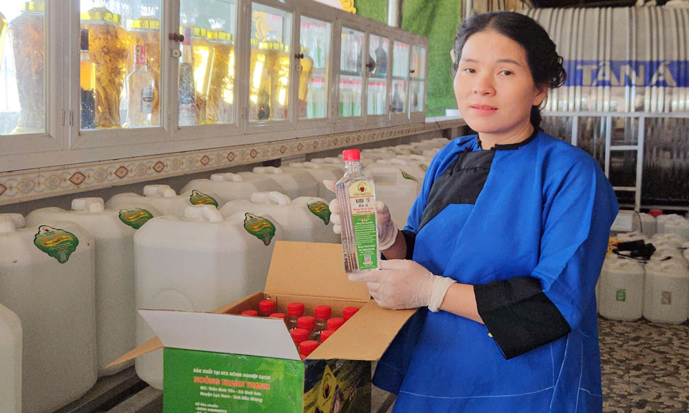 Chị Lương Thị Linh và sản phẩm rượu men lá truyền thống của đồng bào dân tộc Nùng.