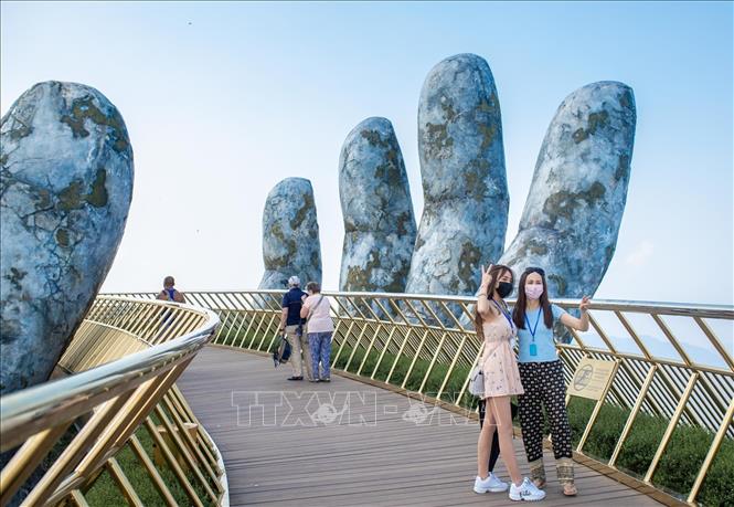 Du khách tham quan chụp ảnh tại cầu Vàng khu du lịch Sun World Ba Na Hills. Ảnh: TTXVN phát