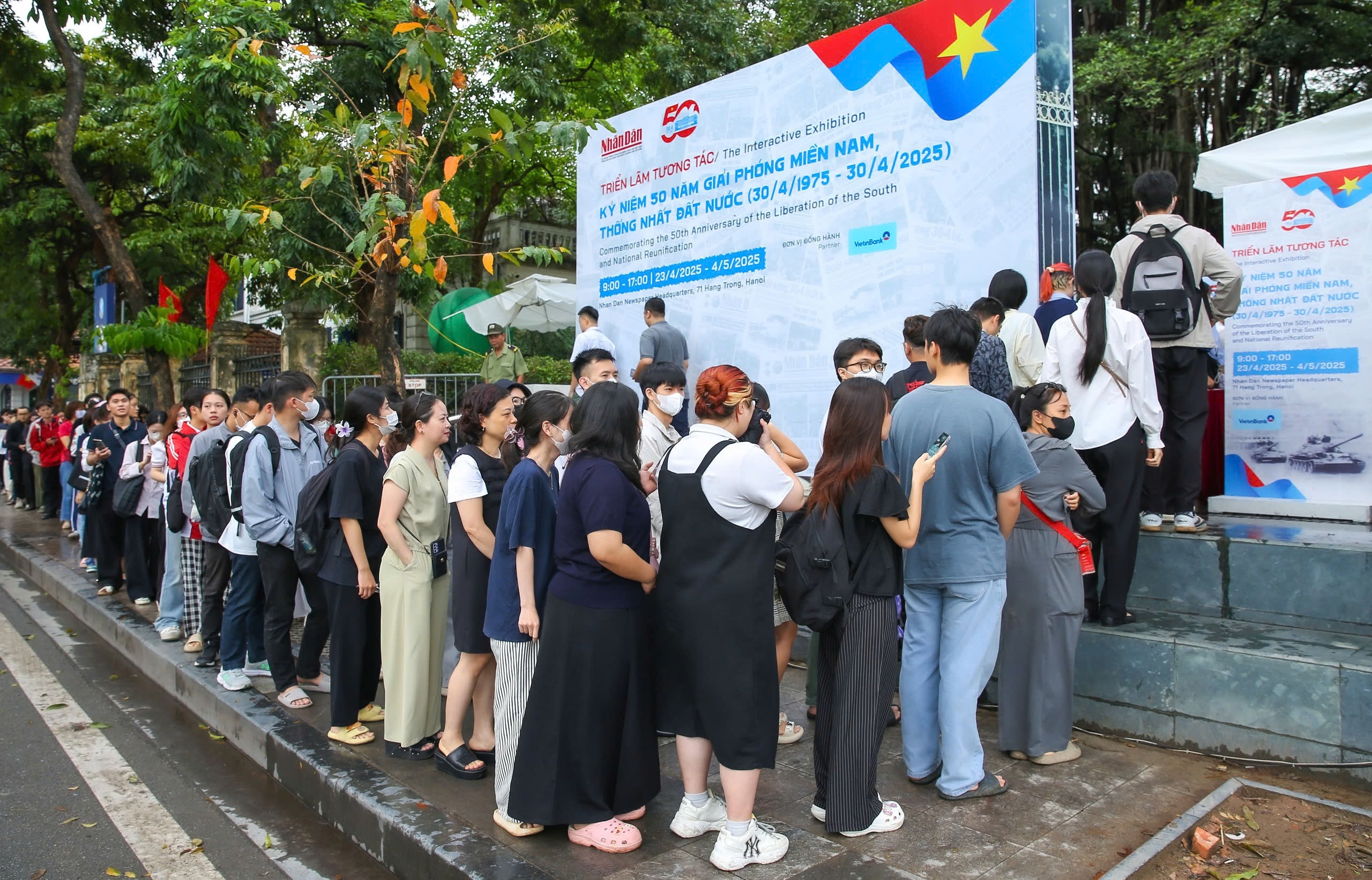 Dòng người xếp hàng dài trên vỉa hè trước trụ sở Báo Nhân Dân, háo hức chờ đợi để vào tham quan triển lãm và nhận ấn phẩm đặc biệt.