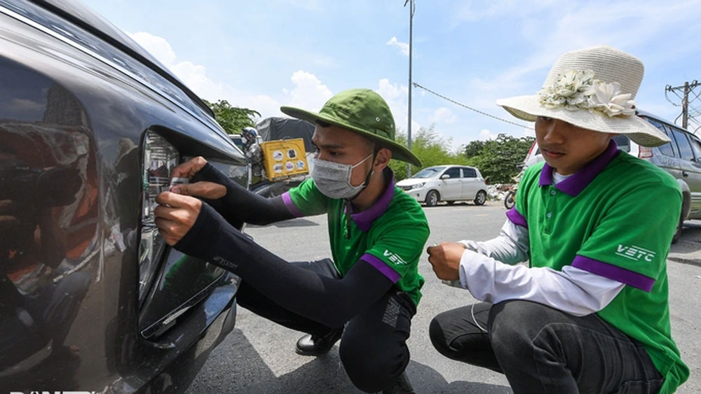 Nhân viên Công ty TNHH thu phí tự động VETC hỗ trợ tài xế dán thẻ ETC.