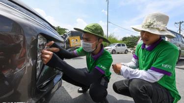 Nhân viên Công ty TNHH thu phí tự động VETC hỗ trợ tài xế dán thẻ ETC.