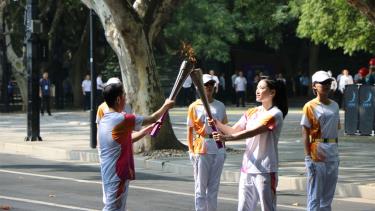 Hai thành viên rước đuốc trao truyền lửa thiêng ASIAD 19. (Ảnh: people.com.cn)